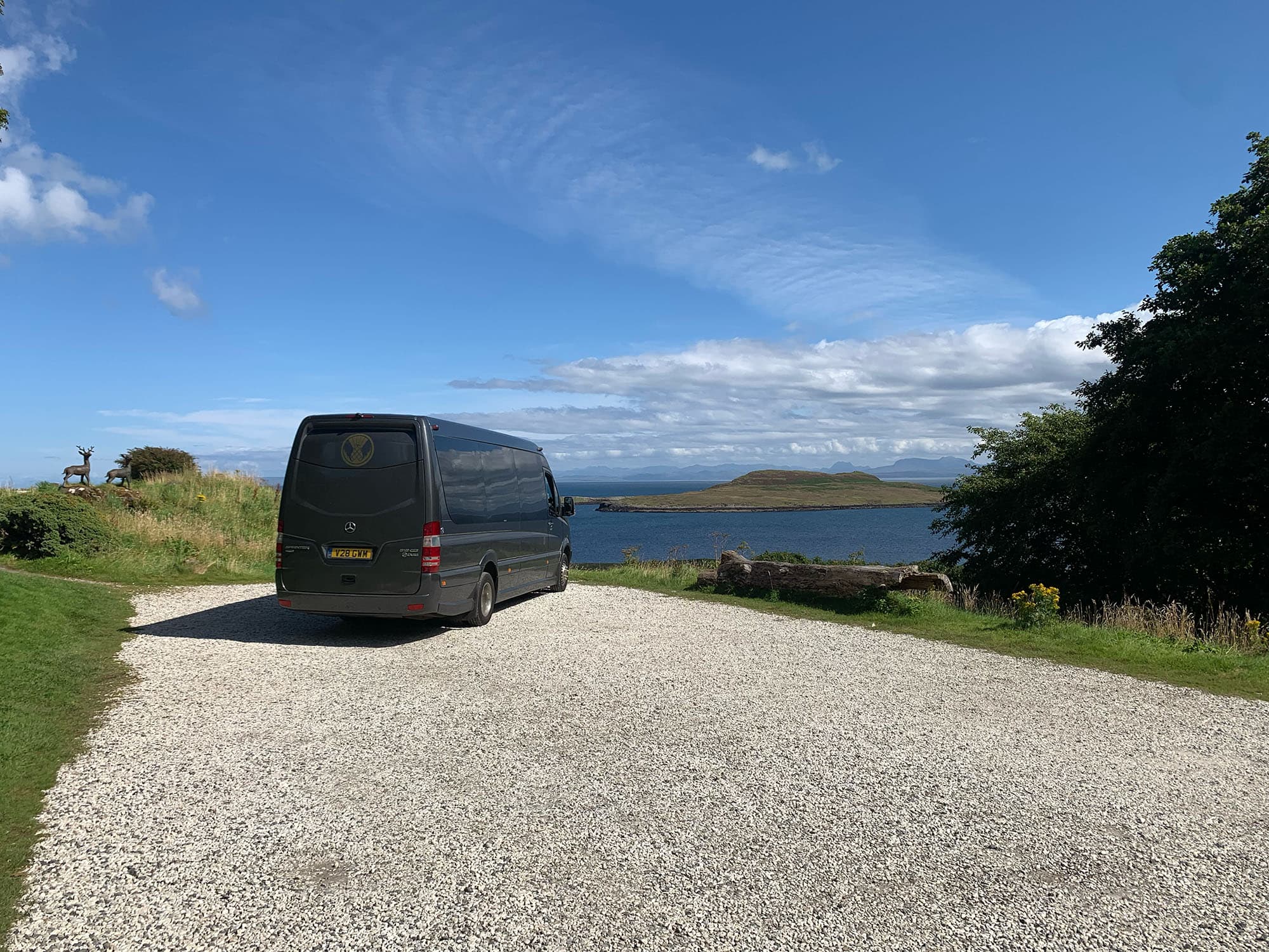 Van next to a body of water with deer in the background